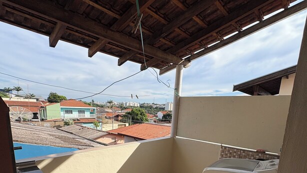 Ein Balkon mit Waschmaschine, Fliesenboden und Blick auf die Nachbarschaft.