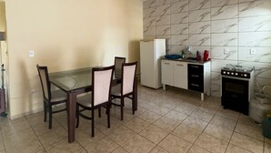 Eine kompakte Küche mit Esstisch und Stühlen, einem Kühlschrank, einem Gasherd und einer gefliesten Spritzschutzwand.