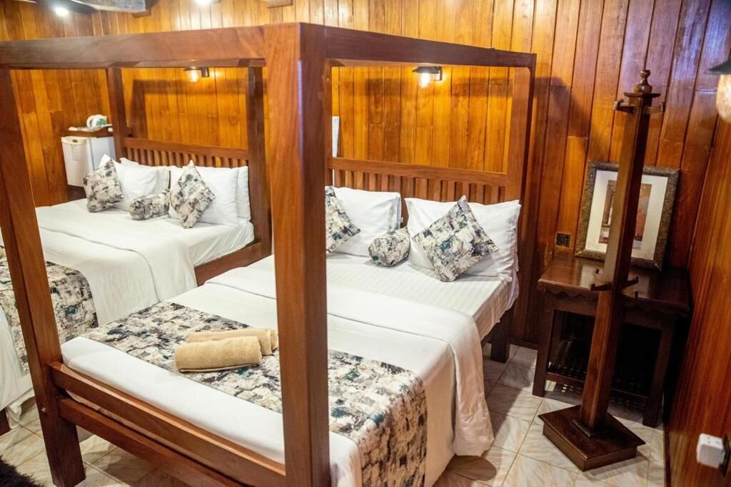 Ein Bett mit Baldachin, belegt mit weißen Leinen und einem floralen Überwurf.