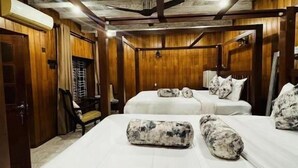 A hotel room with wooden walls and ceiling, two beds with white bedding, a ceiling fan, and a small desk with a chair. - Cara Galle Fort (Galle)