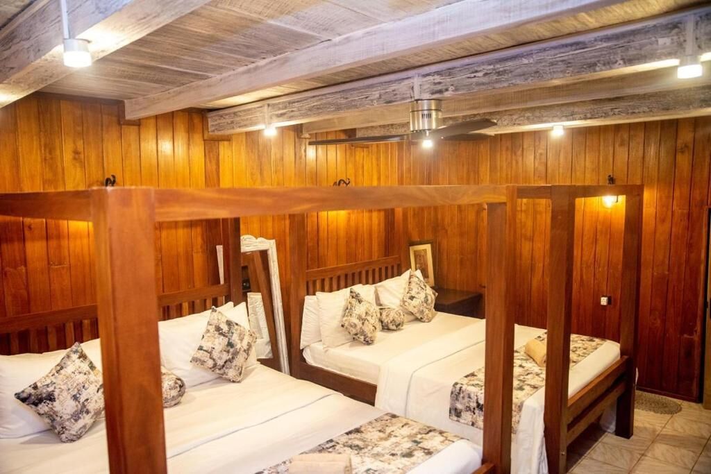 A wooden cabin-style room with three bunk beds, each with a white mattress and patterned pillows.