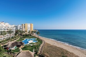 A coastal resort with a swimming pool, beach, and high-rise buildings. - Ground floor 2 bd, 2 bth apt, beachfront complex in Calahonda, Mijas (Mijas)