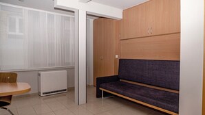 Une pièce avec une armoire en bois, un banc, un radiateur et une fenêtre.