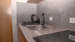 A compact kitchen with a stainless steel sink, a coffee maker, and a kettle. - Enjoyable 1-bedroom apartment in beautiful Stuttgart city center W1_P13 (Stuttgart)