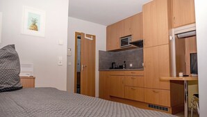 A compact bedroom with a bed, a small kitchenette with a microwave, and a wooden wardrobe. - Enjoyable 1-bedroom apartment in beautiful Stuttgart city center W1_P13 (Stuttgart)