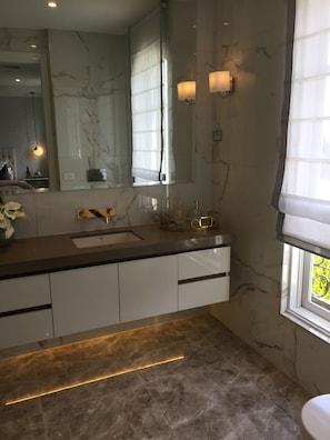 A modern bathroom with a marble vanity, a large mirror, and a window with sheer curtains. - Modern Manor in Melbourne (Burwood East)