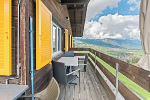 Terraza de madera con asientos exteriores y vista a un valle.