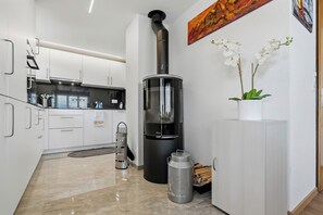 A modern kitchen with white cabinets, a black stove, and a small potted orchid on the counter.