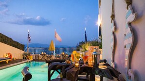 A poolside area with a table set for dining, a cocktail shaker, and a view of the sea. - Castri Village Kythira - Phoenix Sea View Retreat (Kithira)