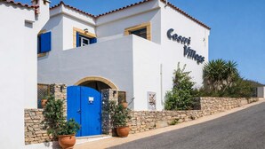 A white building with a blue door and the name 'Castri Villas' on the side. - Castri Village Kythira - Phoenix Sea View Retreat (Kithira)