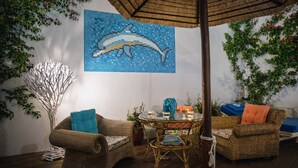 A cozy indoor setting with wicker furniture, a round table, and a wall mural of a dolphin. - Castri Village Kythira - Andromeda Sea View Escape (Kithira)