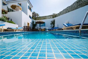 A swimming pool with tiled flooring, lounge chairs, and umbrellas. - Castri Village Kythira - Andromeda Sea View Escape (Kithira)