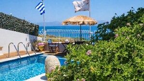 A pool area with a view of the sea, a flag, and a thatched umbrella. - Castri Village Kythira - Andromeda Sea View Escape (Kithira)