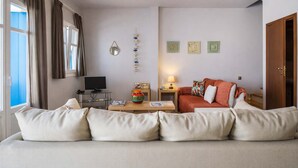 A modern living room with a sofa, a coffee table, a TV, and a lamp. - Castri Village Kythira - Andromeda Sea View Escape (Kithira)
