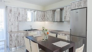 Une cuisine moderne avec des meubles blancs, un réfrigérateur en acier inoxydable et une table à manger avec des chaises.
