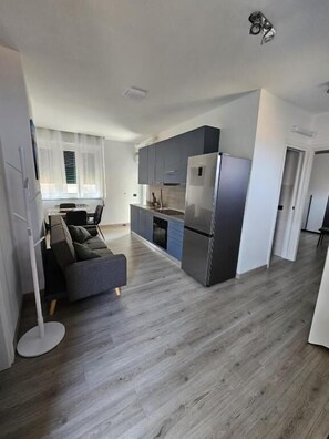 Una cocina moderna con gabinetes grises y un refrigerador de acero inoxidable.