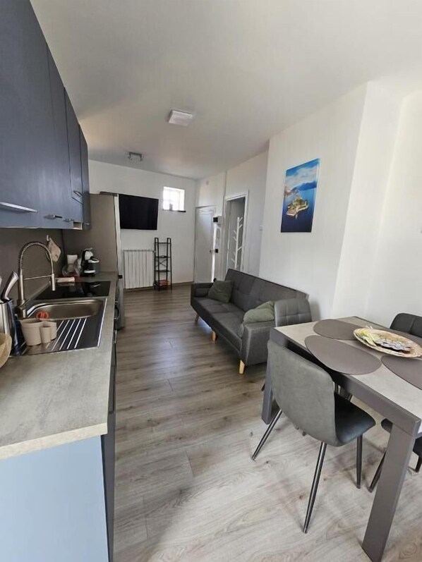 A modern kitchen with a built-in oven, a sink, and a dining area with a table and chairs. - Lake View (Meina)