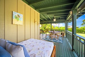 A bedroom with a bed, a painting, a balcony with a table and chairs, and a view of greenery. - Umetsu, Hanalei's Timeless Charm w/ AC TVNC#5096 (Hanalei)