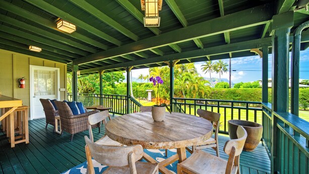 A covered outdoor area with a wooden table and chairs, a potted plant, and a view of greenery. - Umetsu, Hanalei's Timeless Charm w/ AC TVNC#5096 (Hanalei)