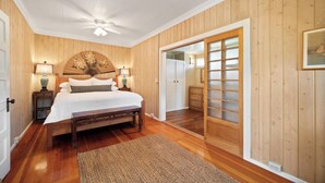 A bedroom with a bed, bedside lamps, a wooden ceiling fan, and a large sliding glass door leading to a closet. - Umetsu, Hanalei's Timeless Charm w/ AC TVNC#5096 (Hanalei)