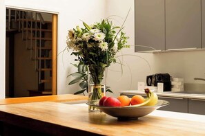 Un comptoir de cuisine orné d’un vase de fleurs et d’un saladier rempli de fruits.