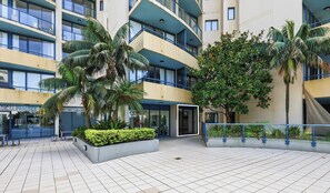A modern building with multiple floors, large windows, and a central courtyard with benches and plants.