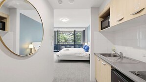 Una camera d'albergo moderna con un letto, un bagno e un angolo cottura.