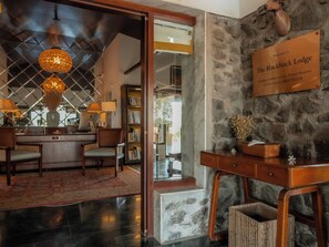 A reception area with a stone wall, a wooden desk, and a chandelier. - The Blackbuck Lodge (Bhavnagar)