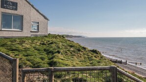 A building with a sign reading 'BEACHROAD ESTATE BAKEHOUSE' and a view of the sea. - Sand Martin (St Bees)