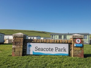 A sign for Seacote Park with a stone wall, a speed limit sign, and a 'Dogs on Leads No Fouling' sign. - Sand Martin (St Bees)