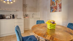 Ein Essbereich mit einem runden Holztisch, blauen Stühlen und einer gelben Vase mit Blumen.