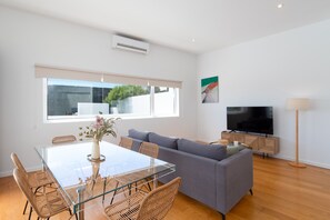 Ein modernes Wohnzimmer mit Glastisch, grauem Sofa und Flachbildfernseher.