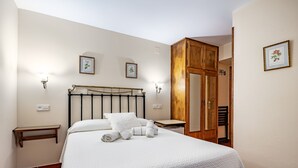 A neatly made bed with a headboard, two bedside tables, and a wooden wardrobe.