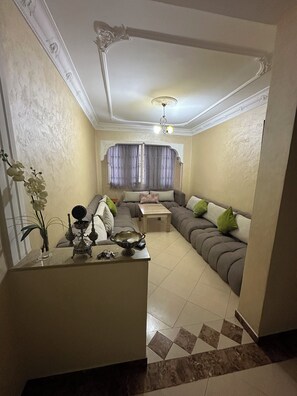 A living room with a sofa, a coffee table, and a decorative bowl. - Cosy room - Chez Redouan 5 minutes from Souk Alhad (Agadir)