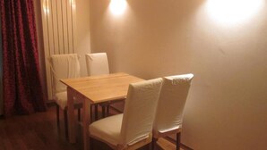 Un'area pranzo con un tavolo di legno e quattro sedie, una tenda rossa e un lampadario a parete.