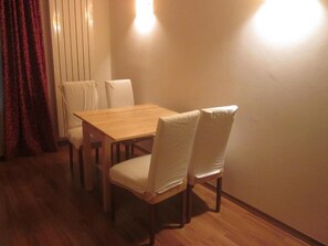A dining area with a wooden table and four chairs, a red curtain, and a wall-mounted light fixture. - 2 rooms apart Venice resorts 1 near bus and train (Venezia)