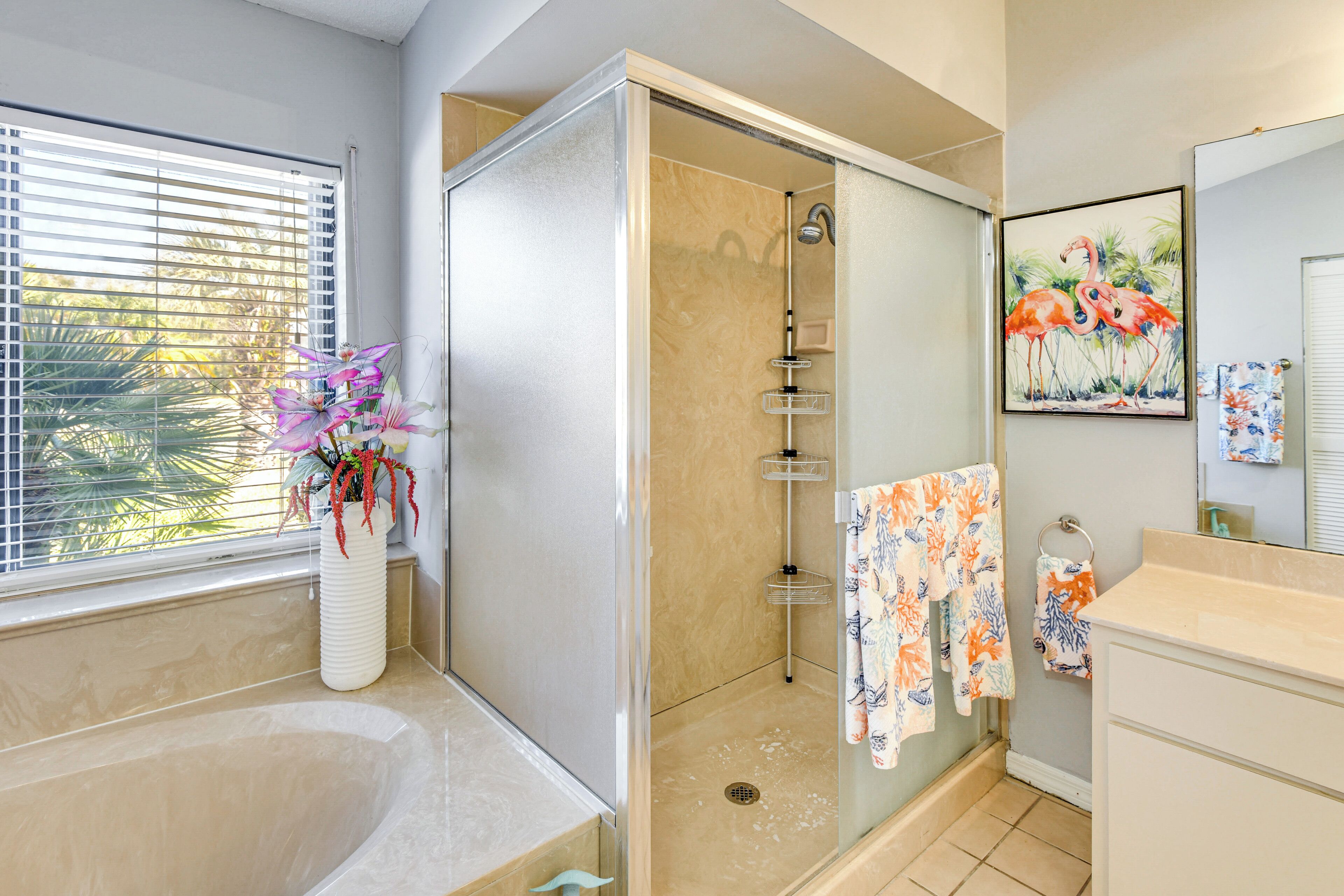 A bathroom with a bathtub, shower, and a window with blinds.
