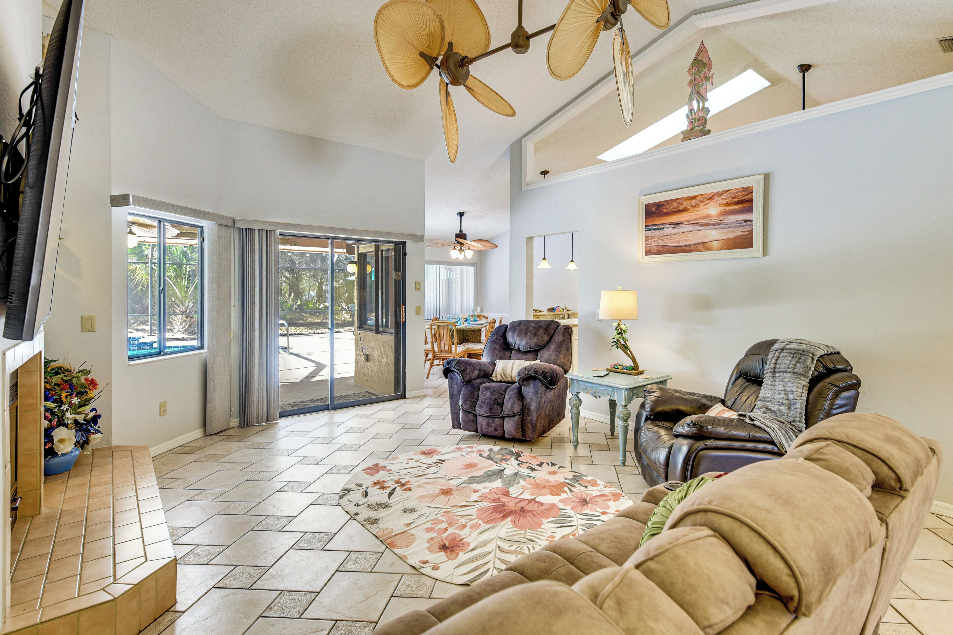 A spacious living area with a large sofa, a recliner, a coffee table, and a ceiling fan.