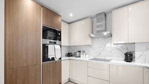 A modern kitchen with wooden cabinets, a stainless steel oven, and a marble backsplash. - The Isleworth 2BR 2BA with Gated Parking & Balcony (Isleworth)