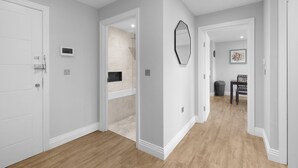 A hallway with a white door, a mirror, and a tiled shower area. - The Isleworth 2BR 2BA with Gated Parking & Balcony (Isleworth)