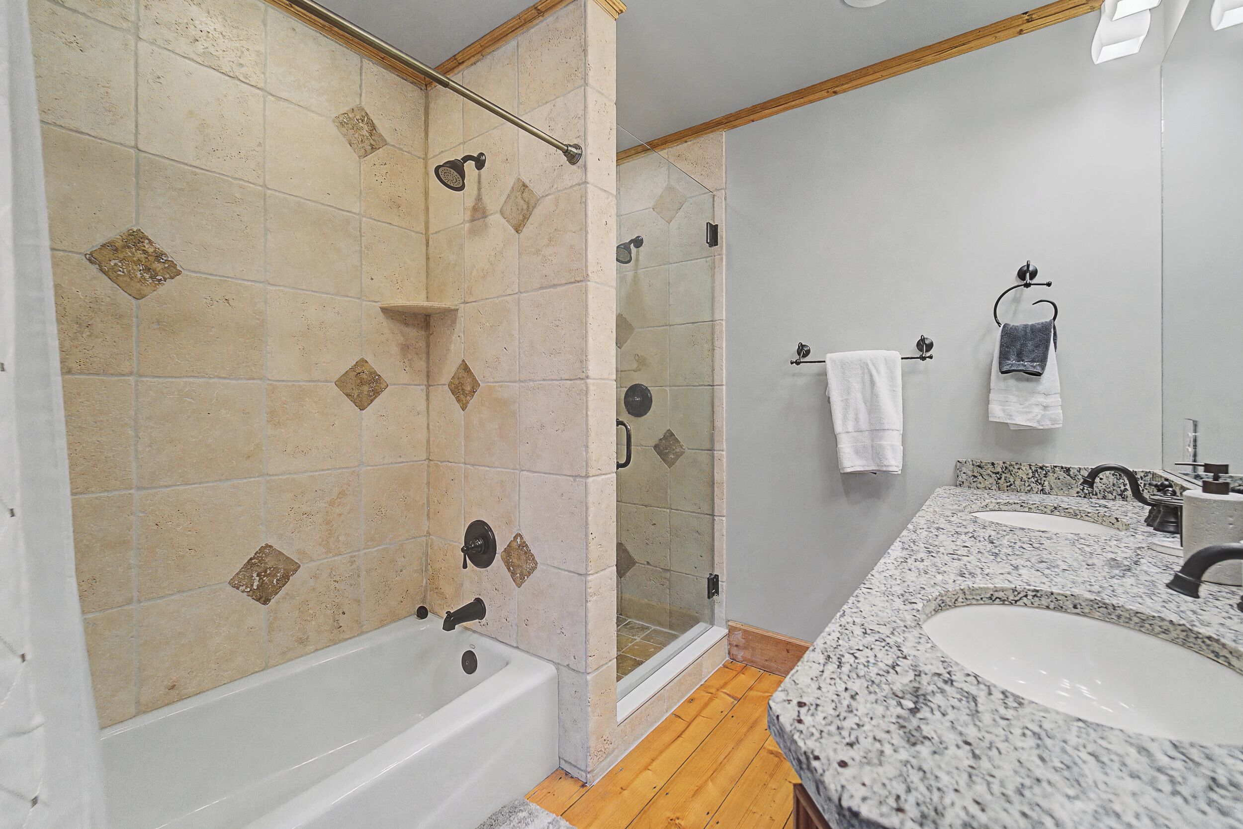 A bathroom with a bathtub, a shower, and a vanity with two sinks.