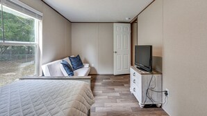 A bedroom with a bed, a TV on a wooden cabinet, a white door, and a window with blinds. - 2 Mi to Ocean! Family-friendly Emerald Coast Haven (Fort Walton Beach)