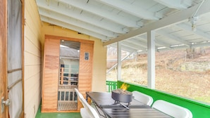 Un espace extérieur abrité, équipé d’une table, de chaises et d’un barbecue.