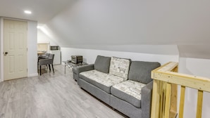 Un petit salon moderne avec un canapé gris, une table basse en bois et une porte blanche.