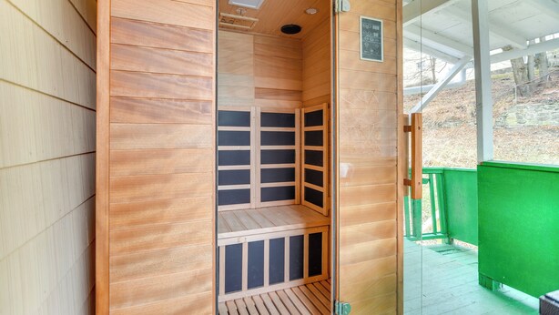 Un sauna avec un intérieur en bois, un banc et une porte en verre.