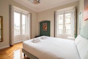 Ein Hotelzimmer mit einem großen Bett, zwei Fenstern, einer grünen Akzentwand und Blick auf die Stadt.