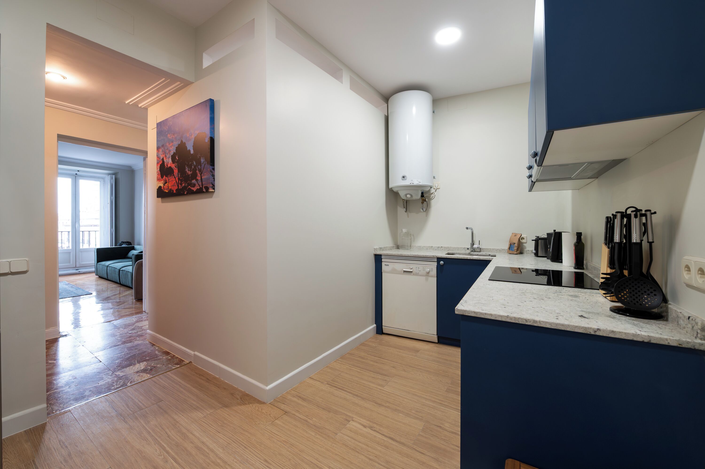 A modern kitchen with a dishwasher, a water heater, and a countertop with kitchen utensils.