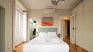 Une chambre spacieuse avec un grand lit, une tête de lit et un tableau représentant un paysage désertique.