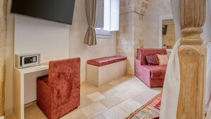 A room with a TV, a red chair, a bench, a pink sofa, and a patterned rug. - Antony Suite Strada Apartment with Wi-Fi and Air Conditioning (Lecce)