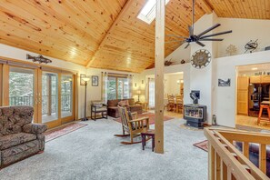 A spacious living room with a high ceiling, wooden beams, a fireplace, and a view of the outdoors. - Deck + Game Room: Secluded Cabin Near Lake Cascade (Cascade)